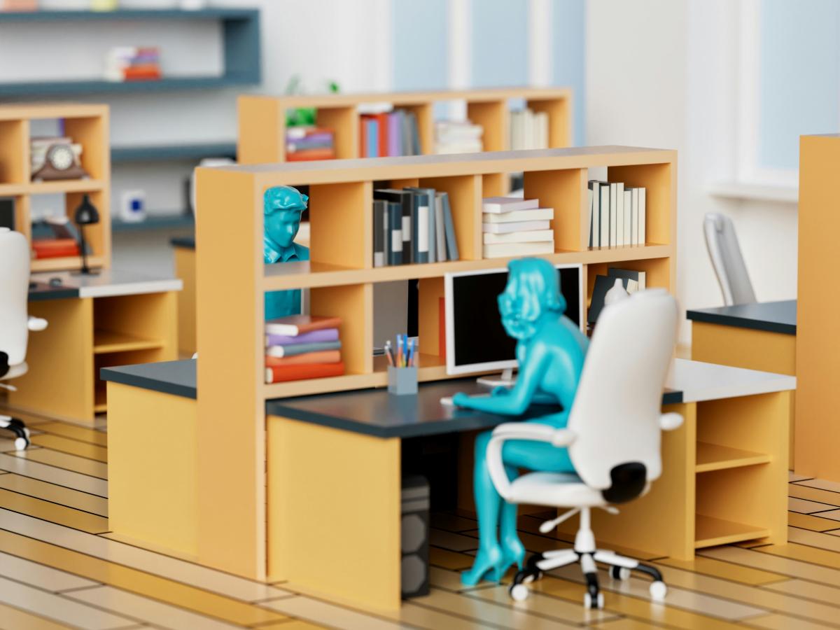 A model of an office desk and shelves, at which a green plastic person sits leaning into the desk.