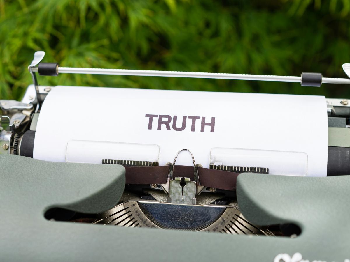 A typewriter holds a piece or paper reading 'truth'