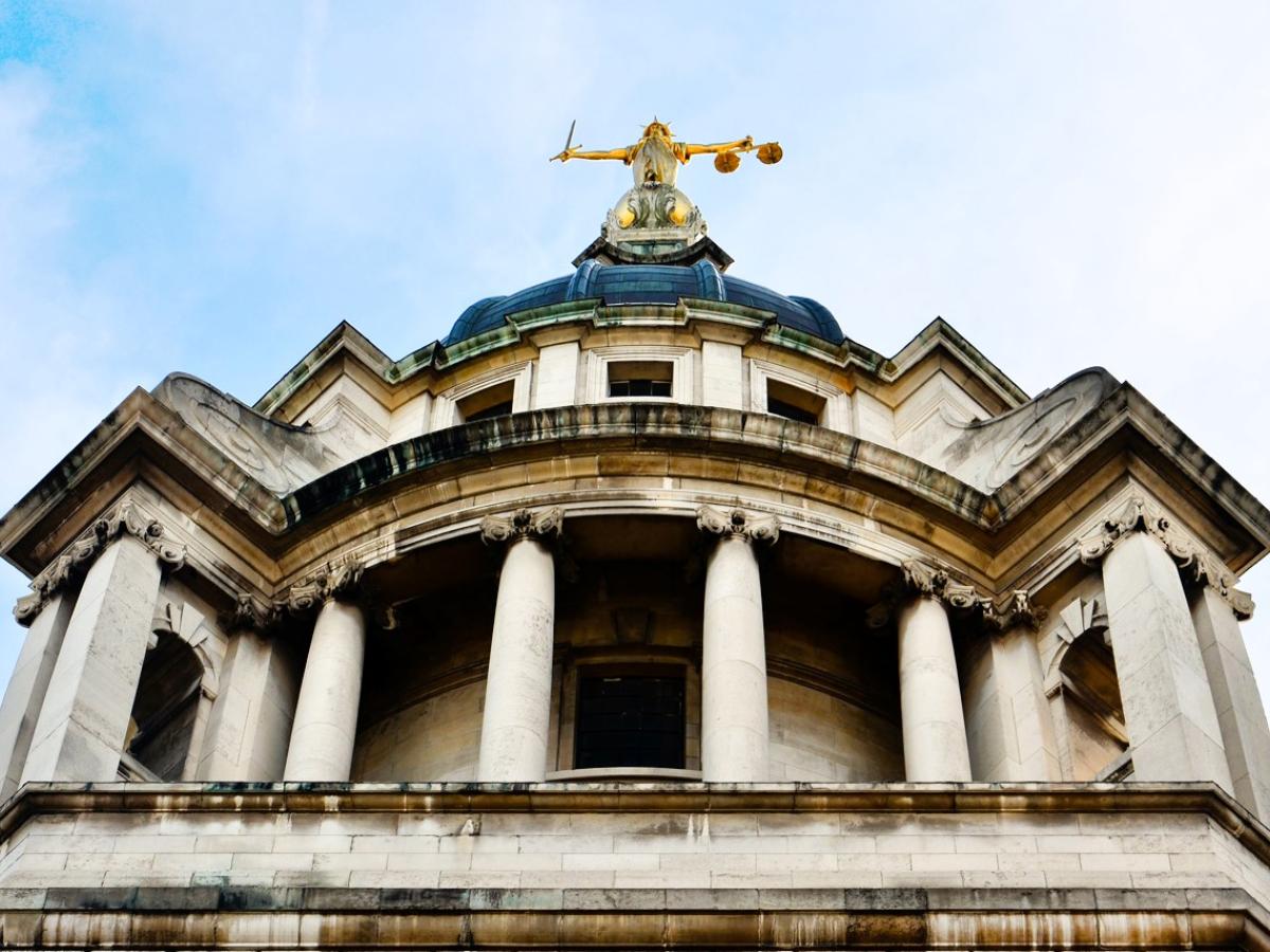 A classical court house with a statue on top of a dome.