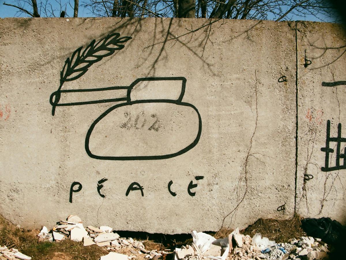 Graffiti of a tank with a peace laurel coming out of its barrel.