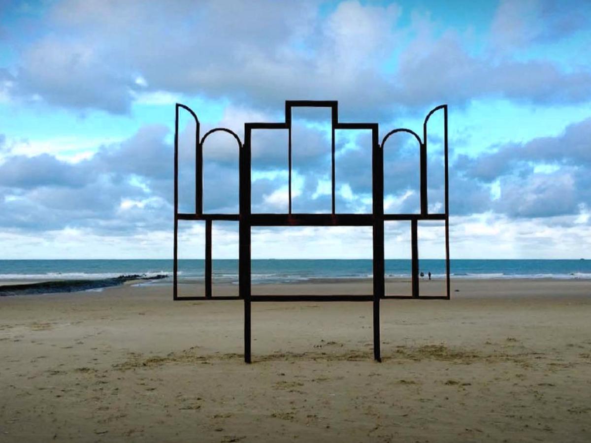 A metak sculpture outlines an altar, stands on a beach.