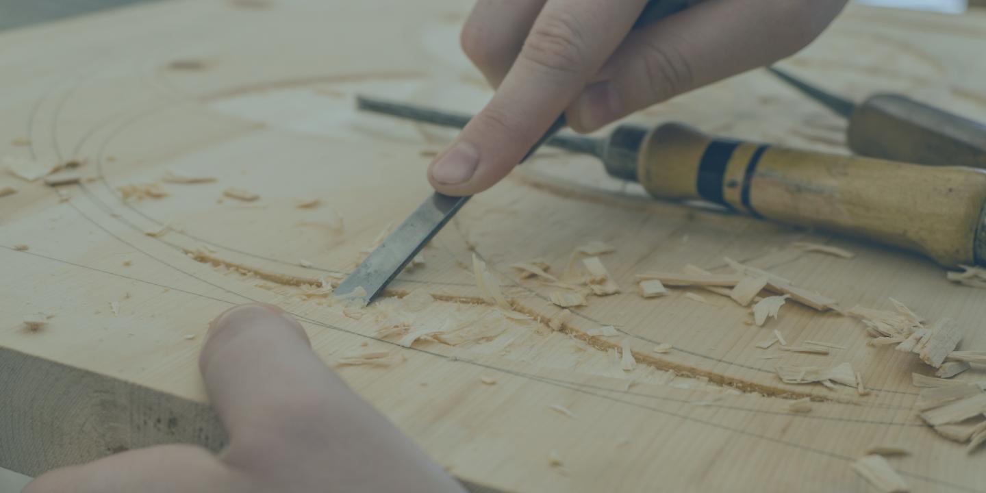 A carving tool is pressed into a groove in wood.