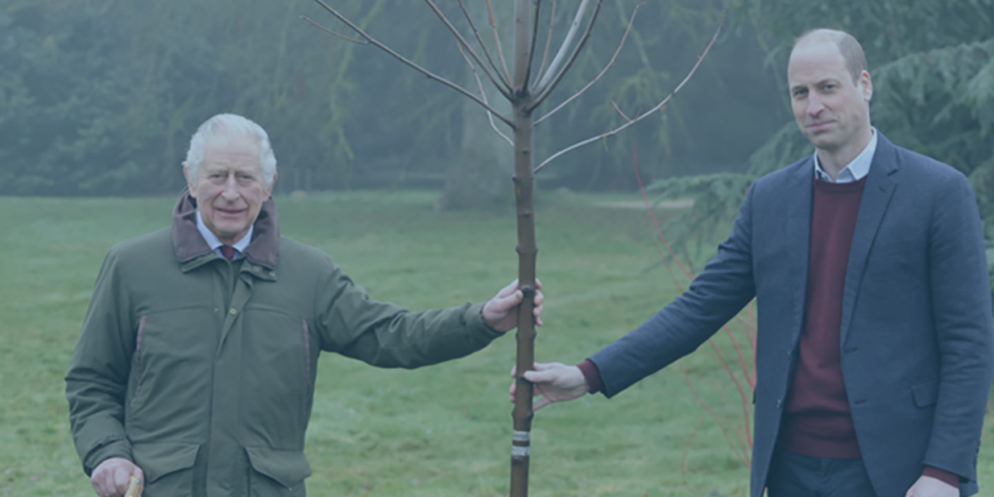 King Charles and Prince William hold a tree sapling upright.