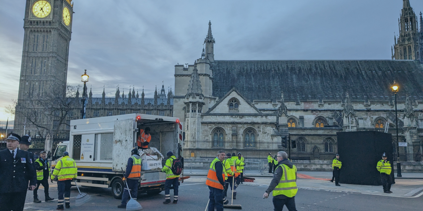 A team of street sweepers clear up the road after the coronation procession, outside the Houses of Parliament.