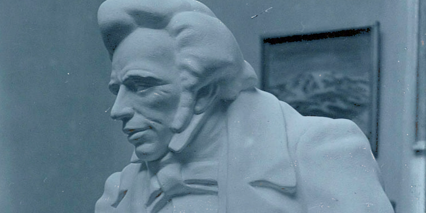 A sculpture of a early 19th century man with a quiff and sharp suit.