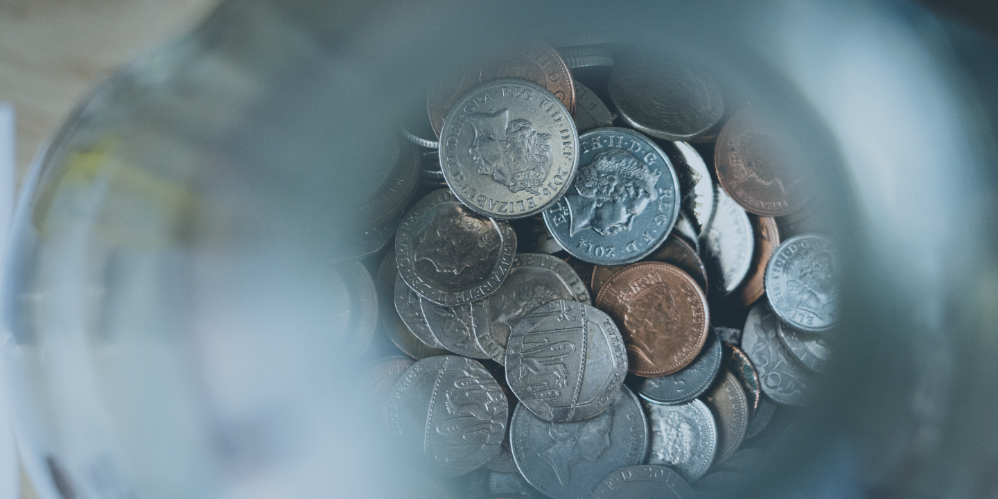 A pile of coins in focus at the bottom of an out of focus glass tube.