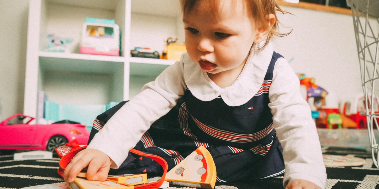 A baby plays with wooden toys on a carpert.