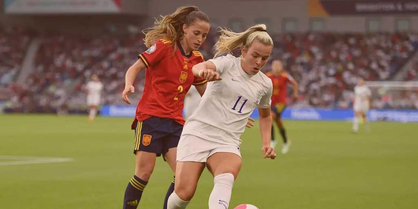 Two footballers run in step as one tries to tackle the other