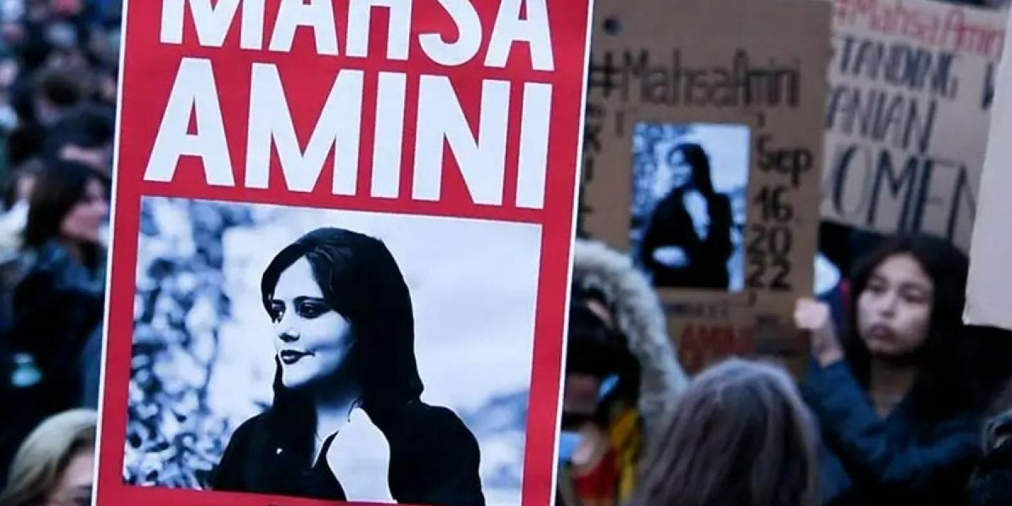 A protester holds a red placard bearing the name and image of Mahsa Amini