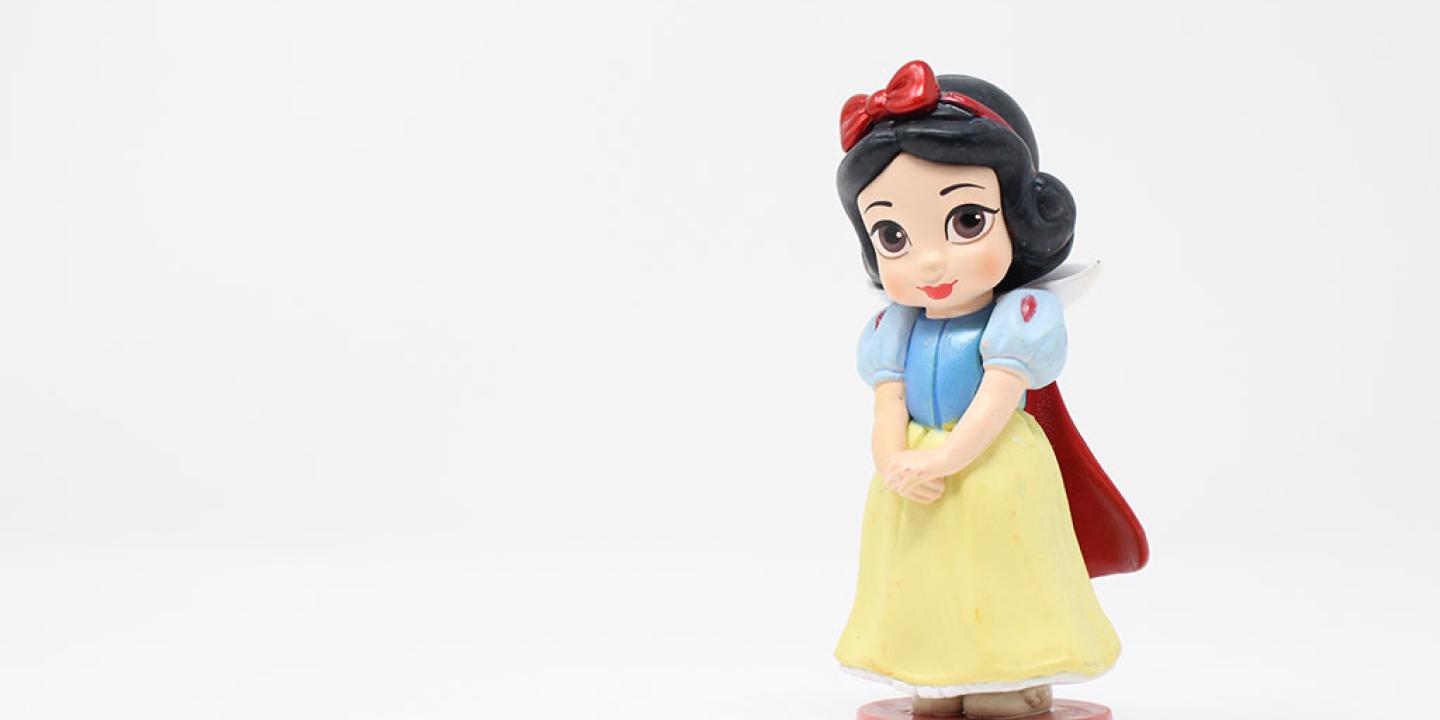 A plastic wind-up Snow White toy stands to the right of the photo, with hands clasped waiting