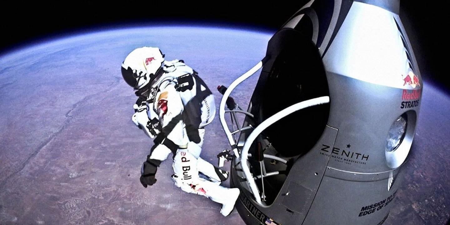 A skydiver in a space pressure shoot leaps from a capsule above the earth.