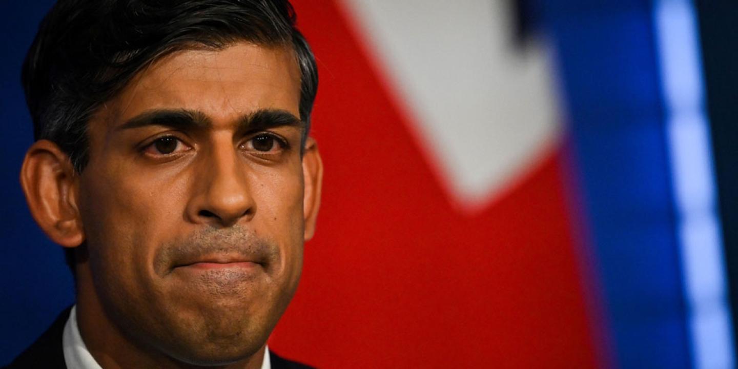 A cropped image of the face of RIshi Sunak with colours of a flag behind him