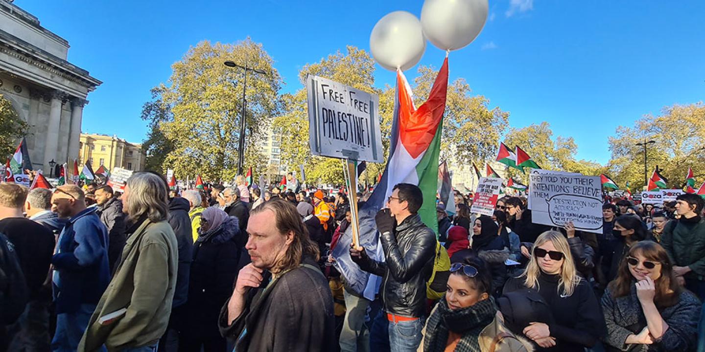 A crowd of people on a protest march file down the street in one directions.