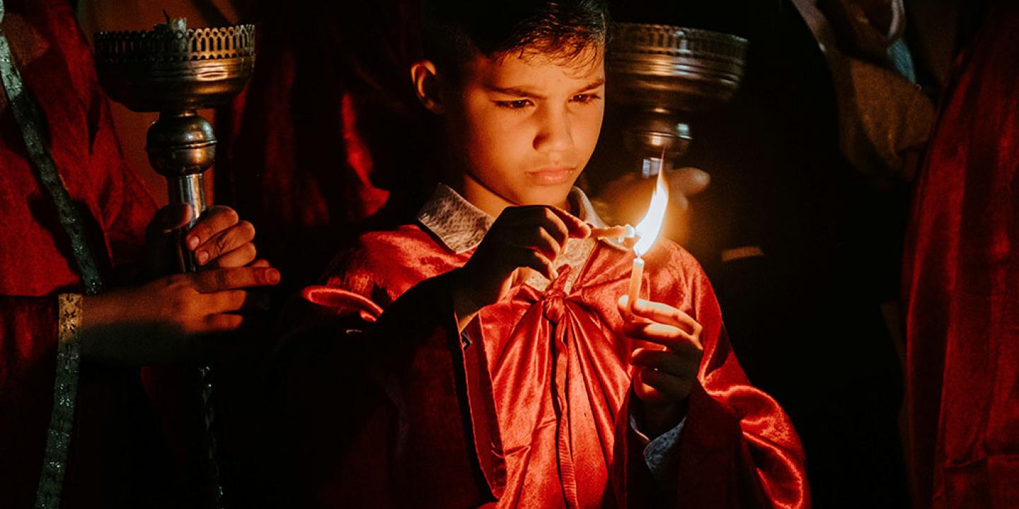 A boy concentrates hard as he holds one candle to another to light it.