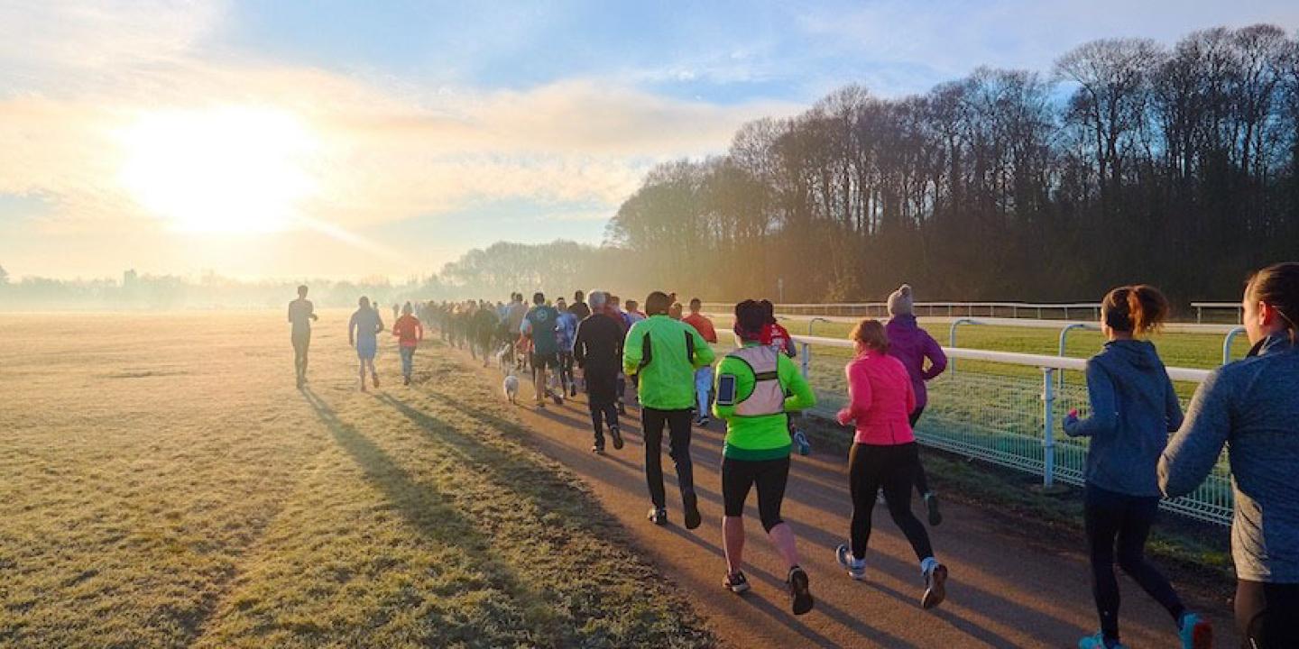 Runners jog along a path into the sunset.