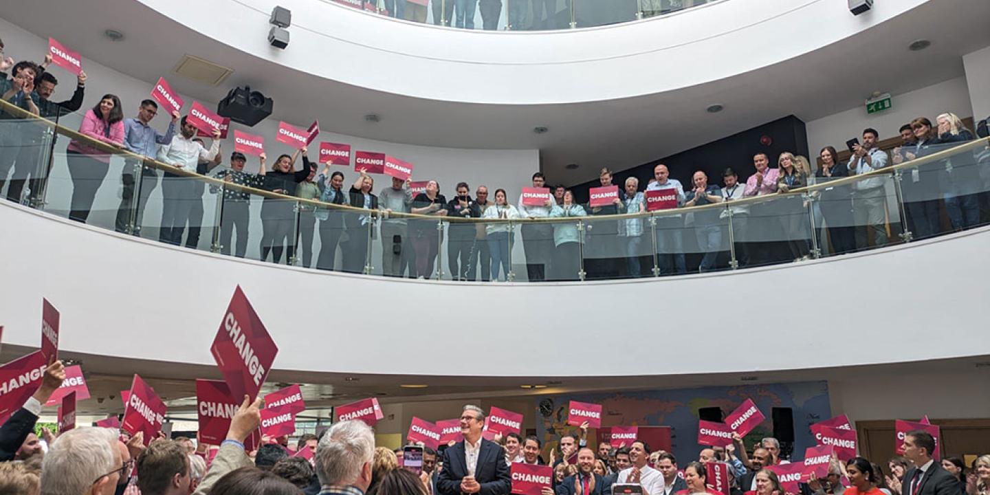 Looked down upon by crowds in galleries, a politician stands amid a throng of supporters