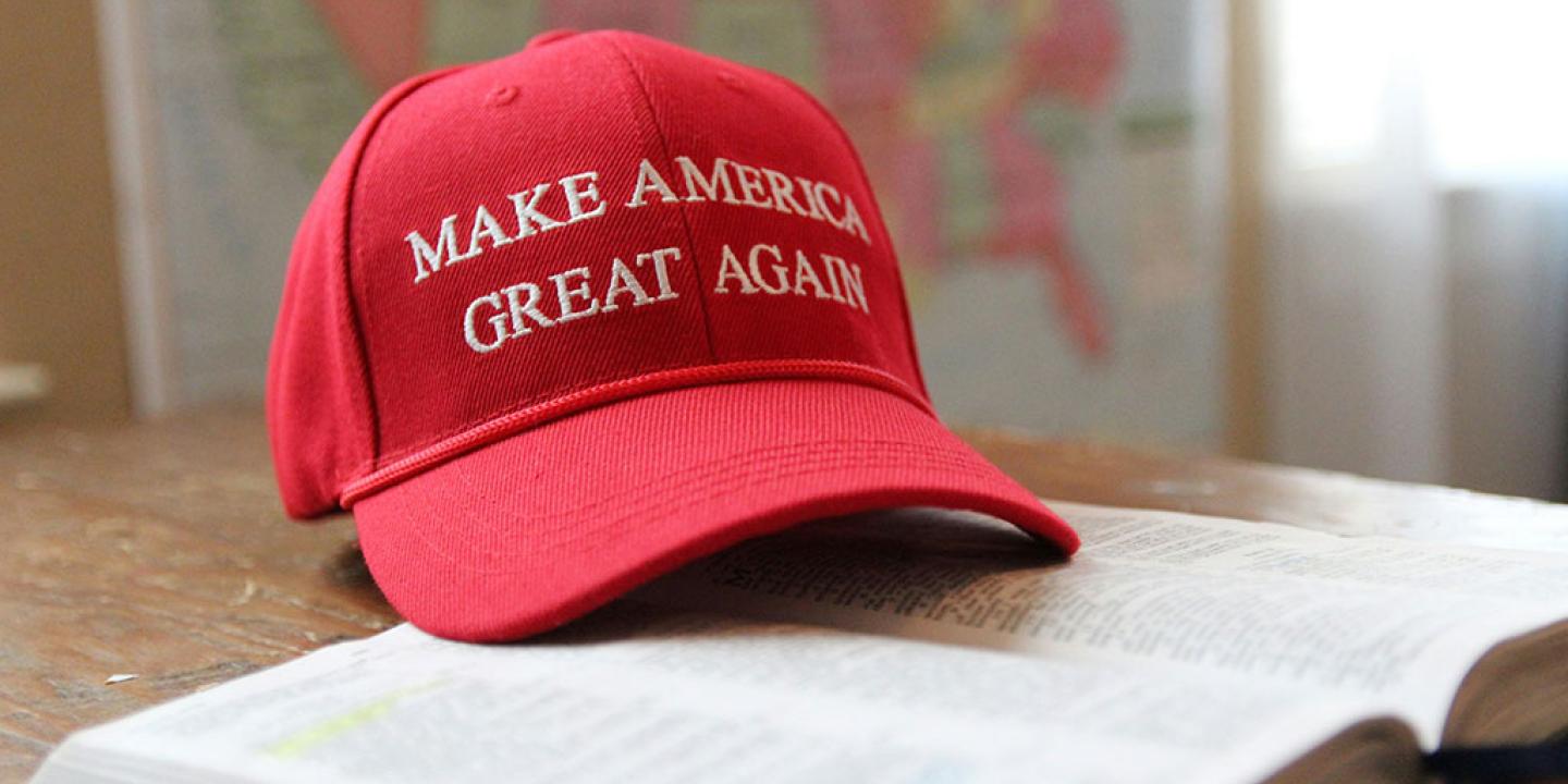 A red baseball cap, with Make America Great Again written across it, sits on an open bible.