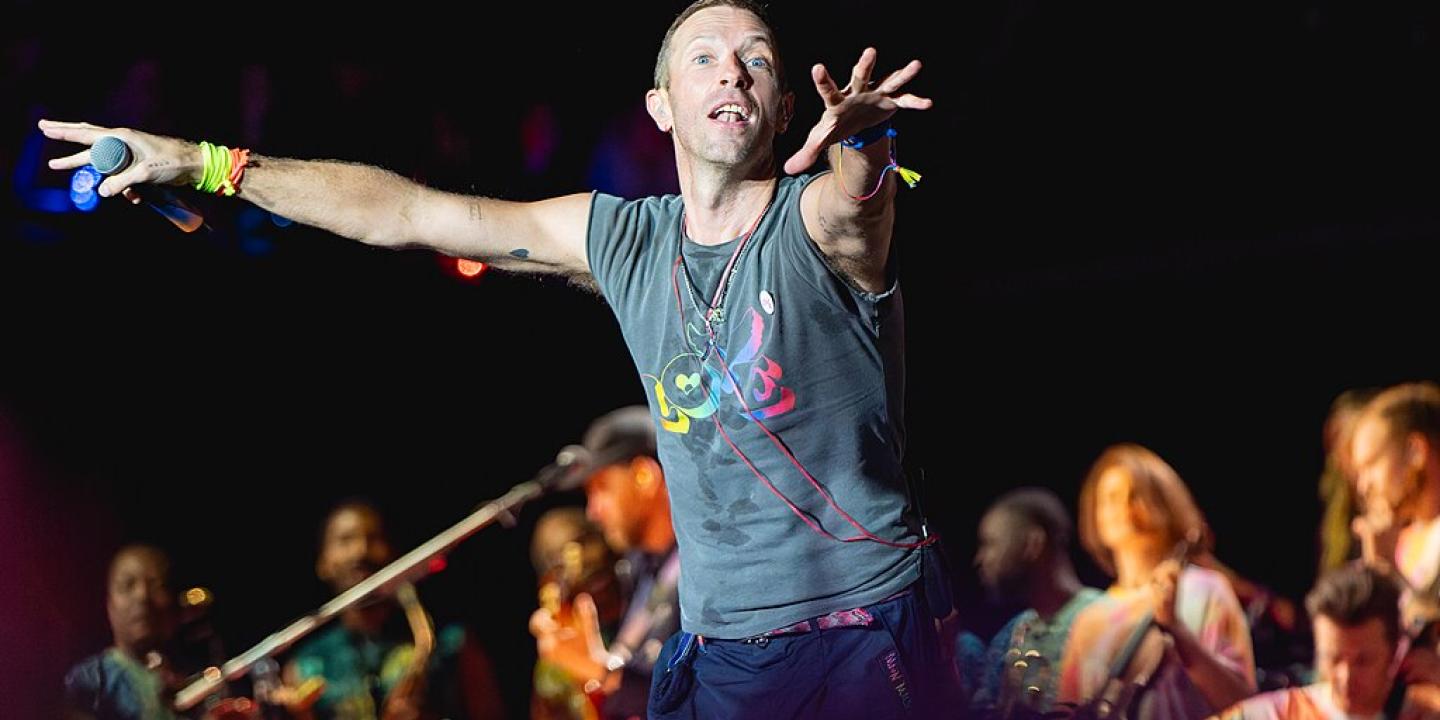 A singer on a stage holds out his arms to conduct the crowd.