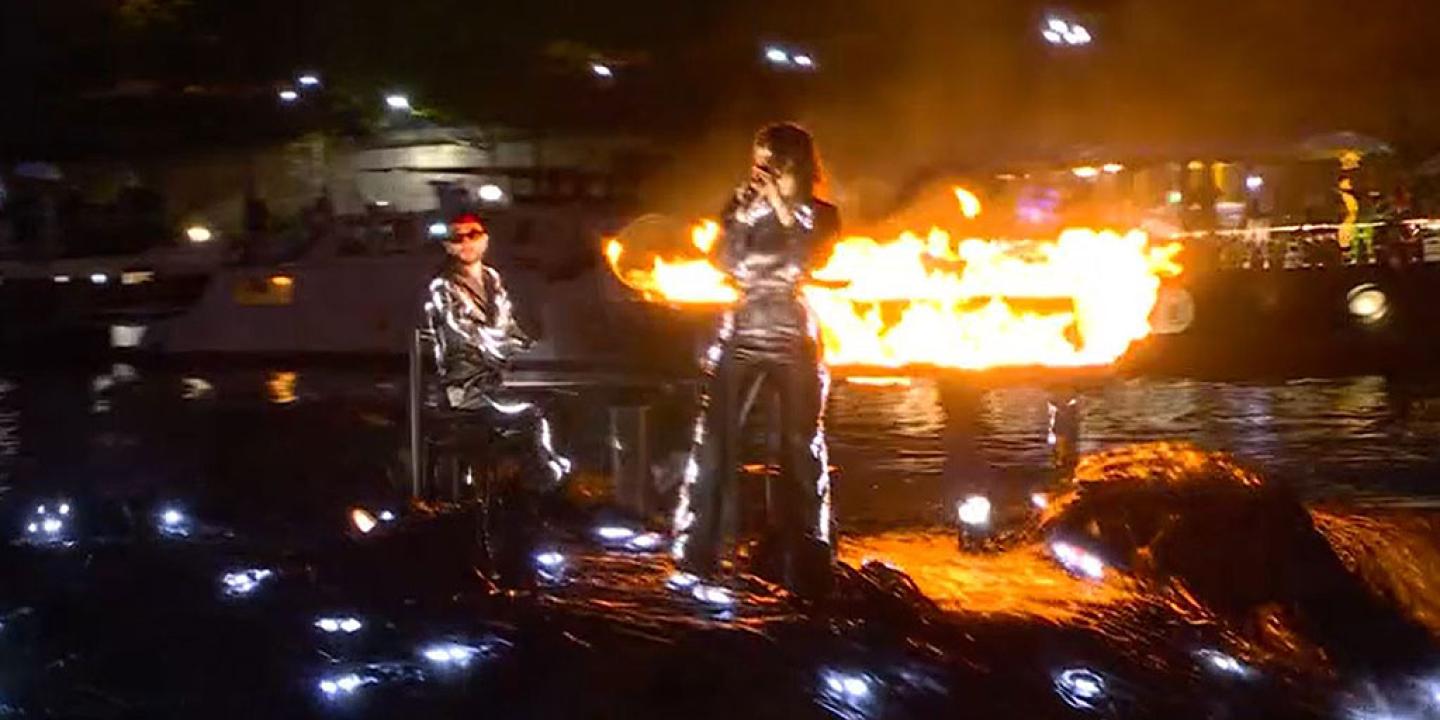 A floating stage bears a flaming piano and singer standing at a mic.