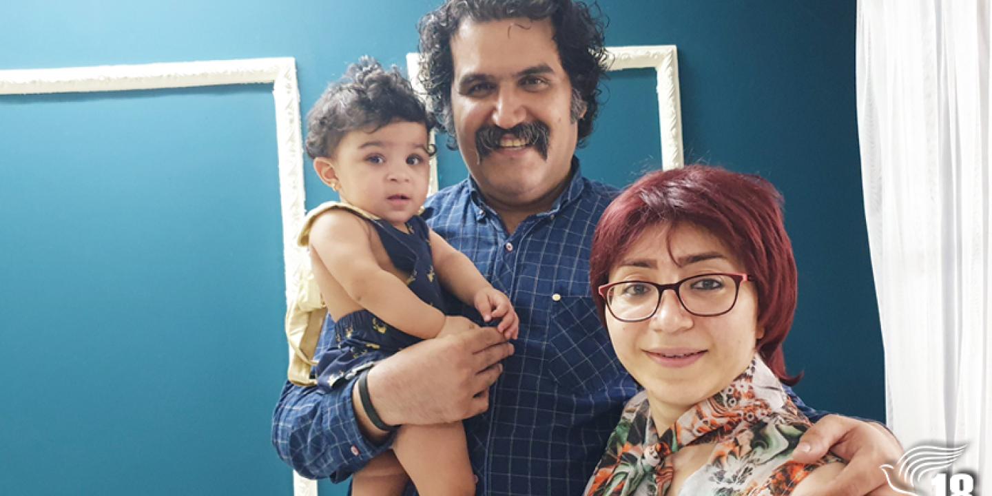 A toddler is held by her father while he stands next to her mother.