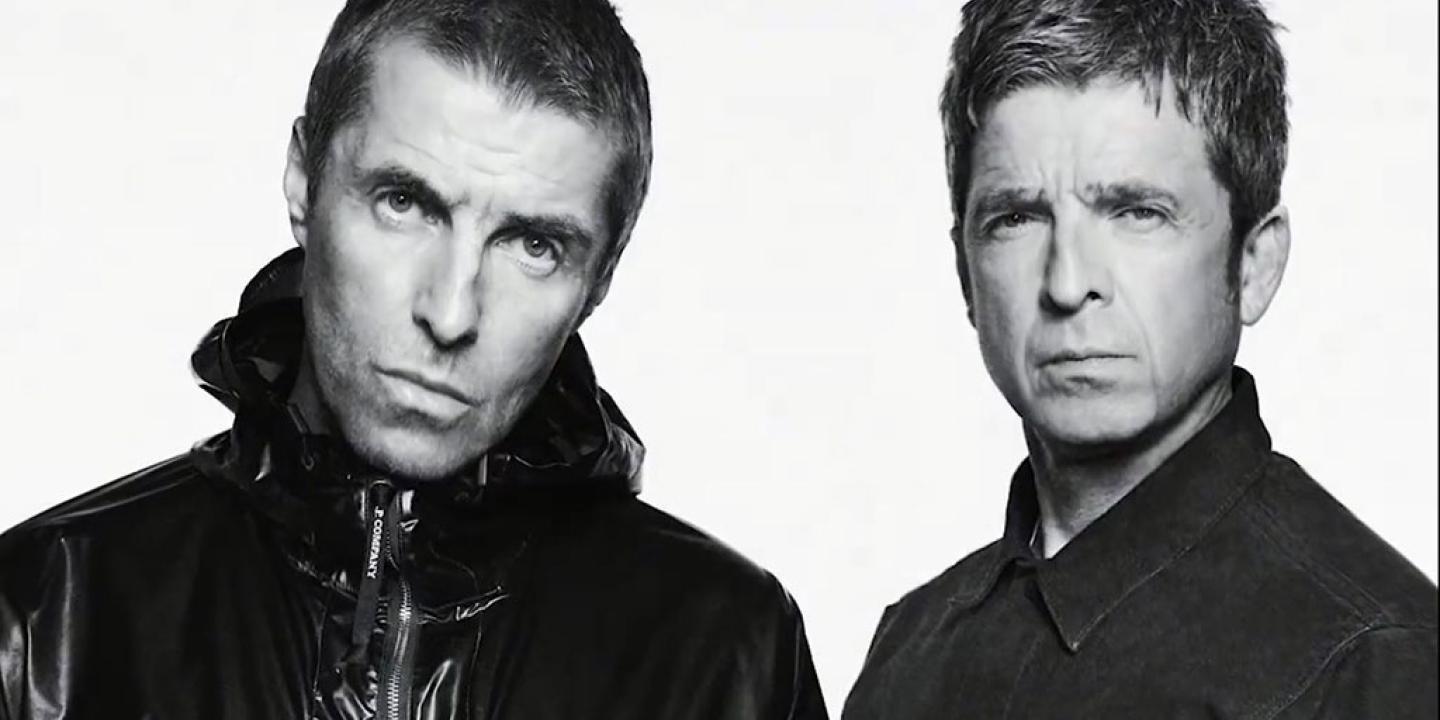 Two middle age rock star brothers pose for the camera in a black and white picture