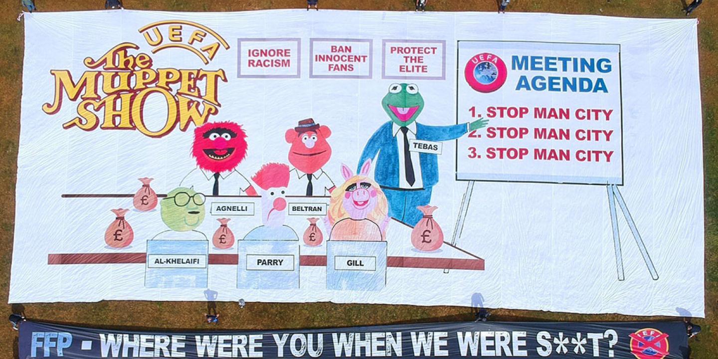 A football support protest banner depicts The Muppet Show logo, a meeting of men in suits and various slogans.