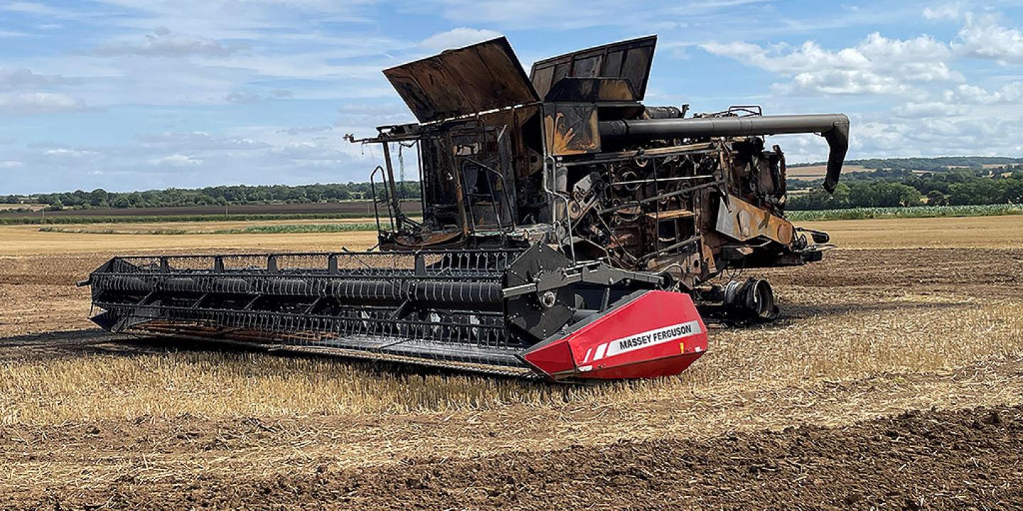 A soot stained burnt-out harvester sits in a recently harvested field.