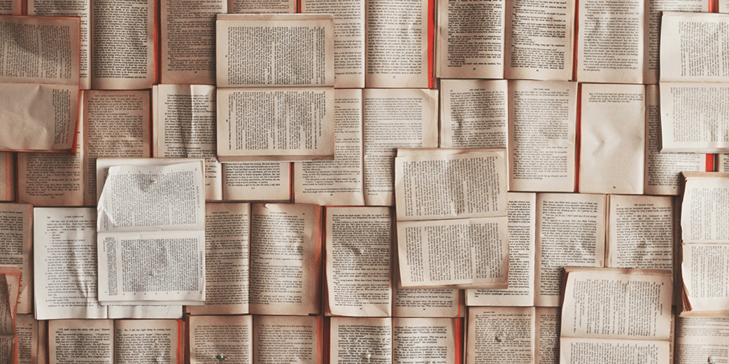 Pages from books are pinned across wall.