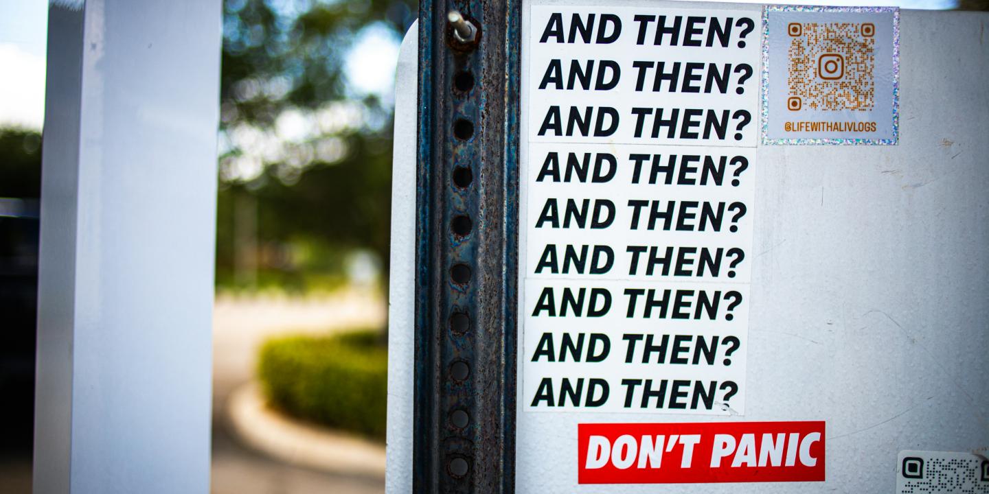 A street sticker displays multiple lines reading 'and then?'