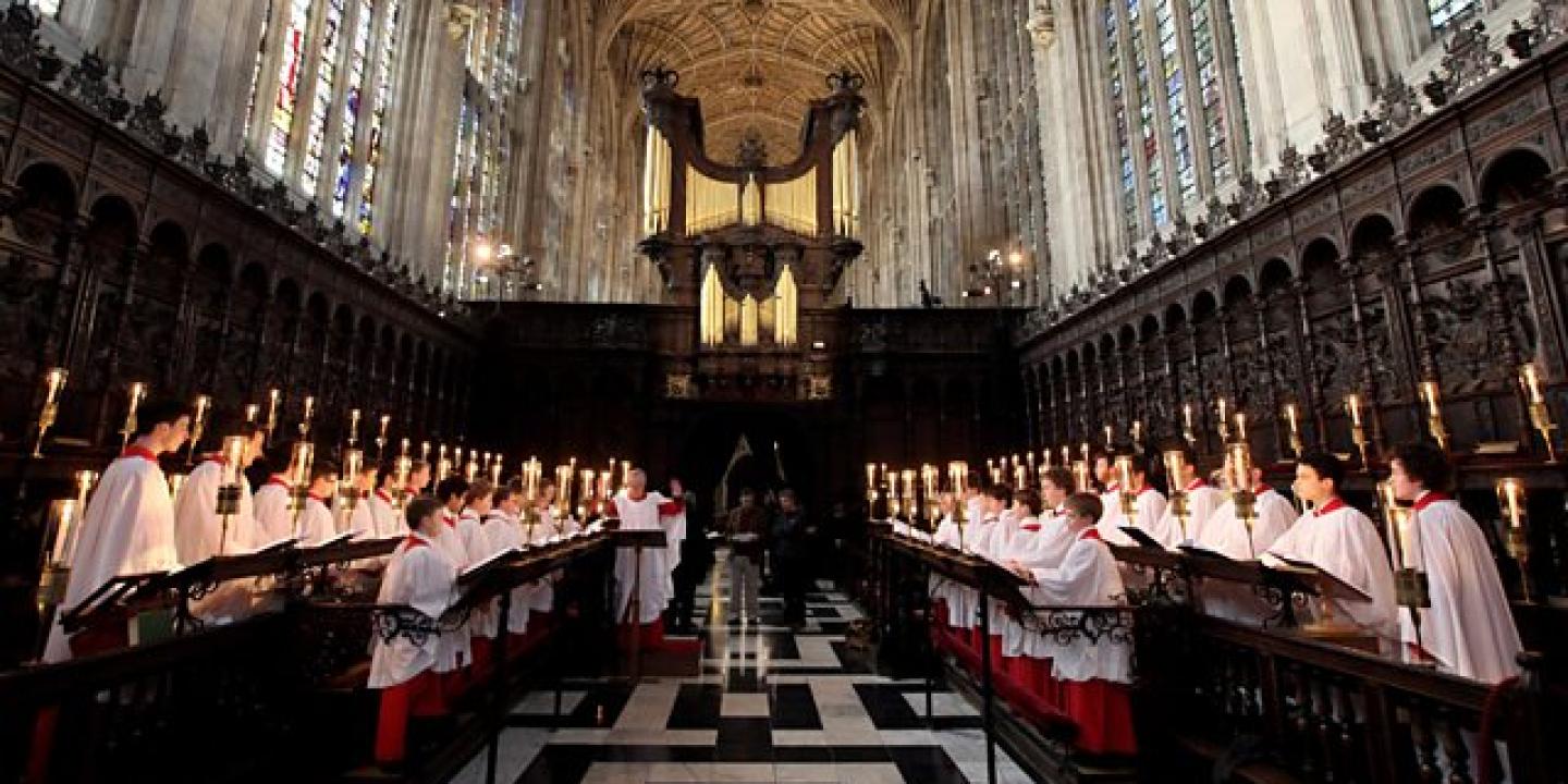 Choristers stand and sing in choir stalls in a church