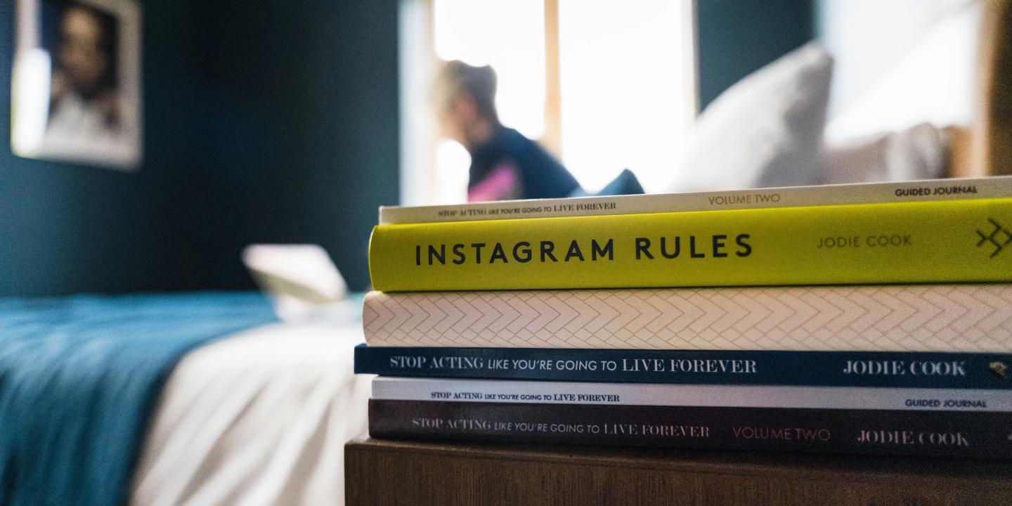 A pile of books on a bedside table.