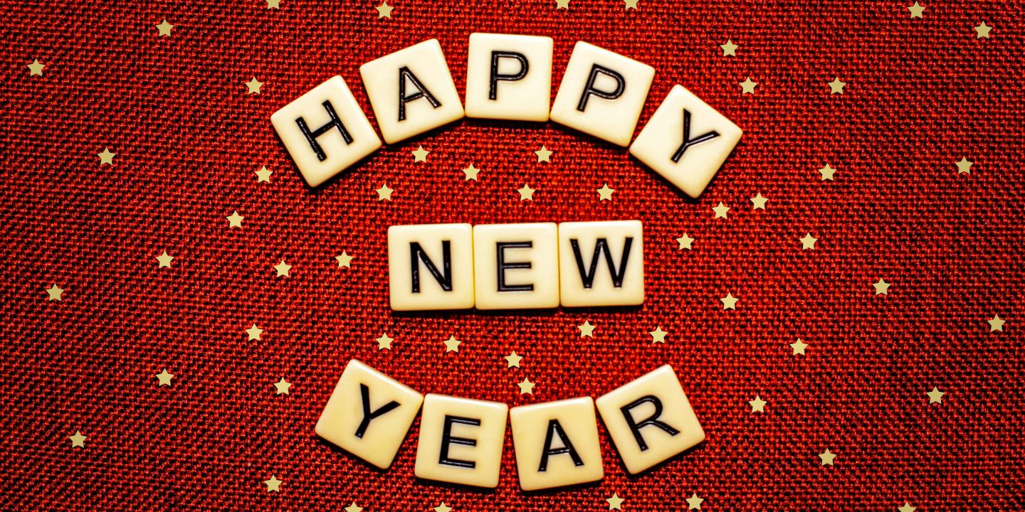 Scrabble letters read 'Happy New Year' against a red starry background.