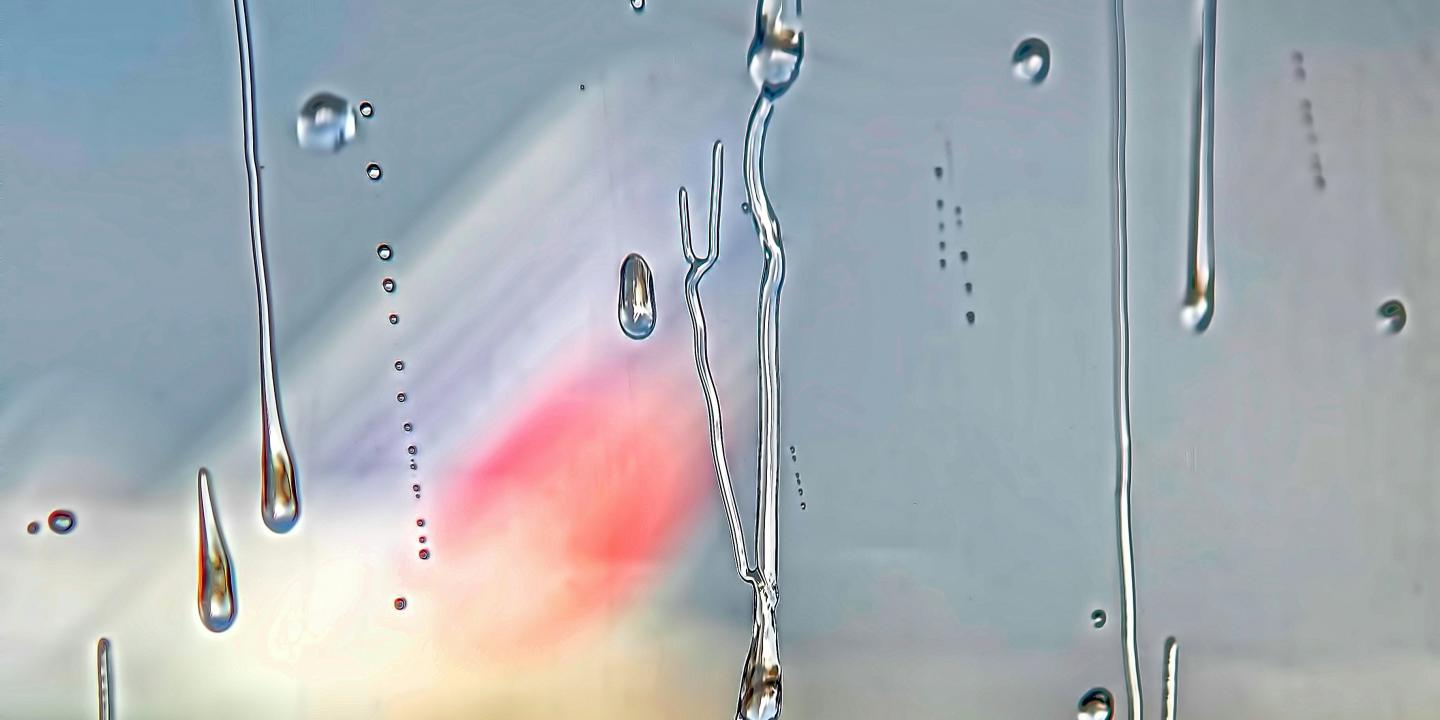 Beyond a misty and raindrop streaked window, a colourful triangle shape emerges.