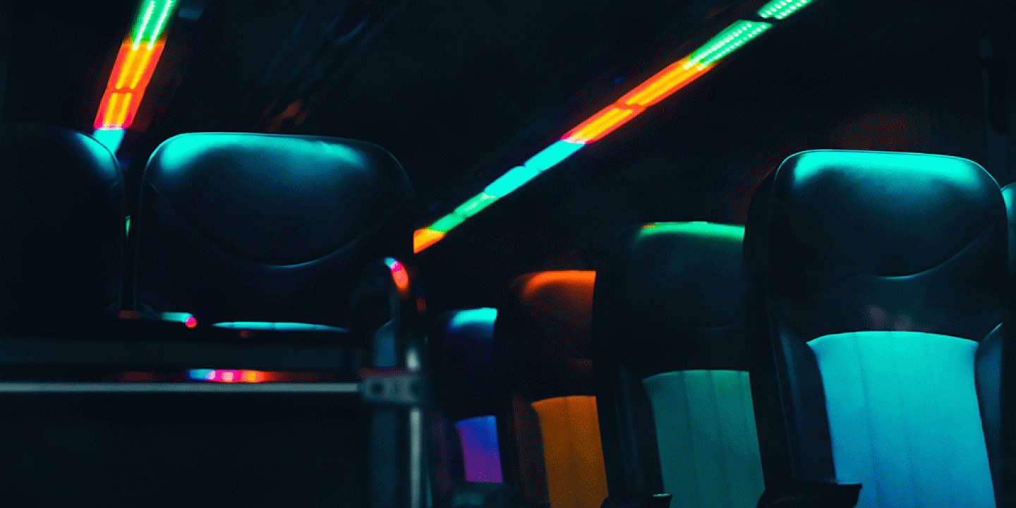 Empty bus seats are lit in dark neon colours.