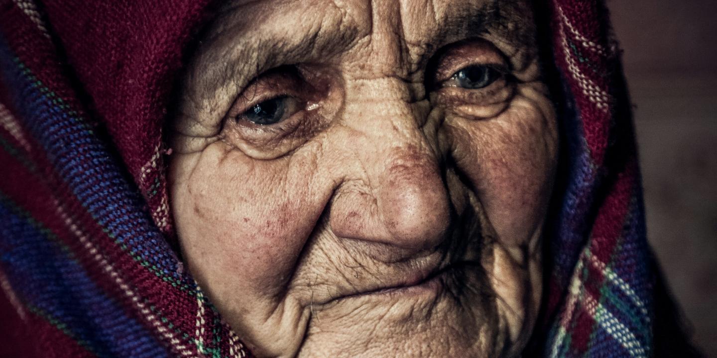 An old woman wearing a shawl looks pensive.