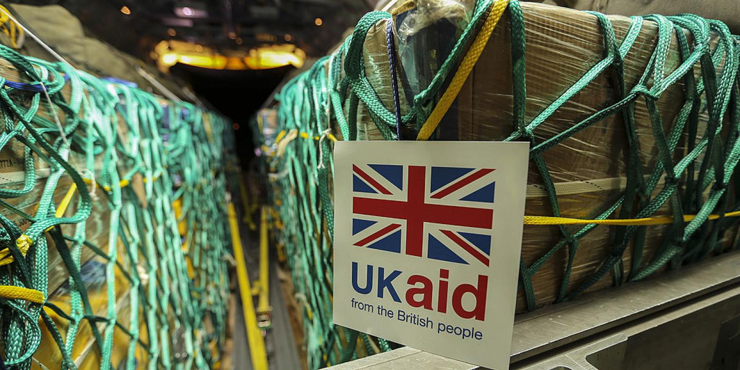 Cargo sits in nets inside a plane, a sign reads 'UK Aid'