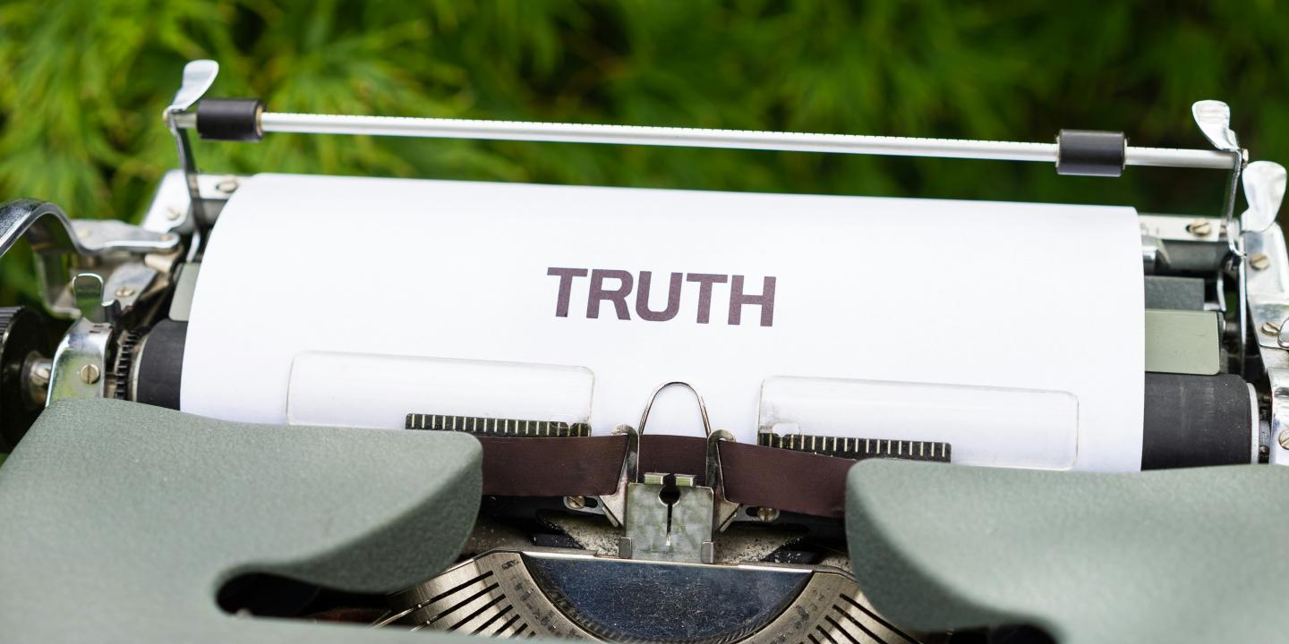 A typewriter holds a piece or paper reading 'truth'