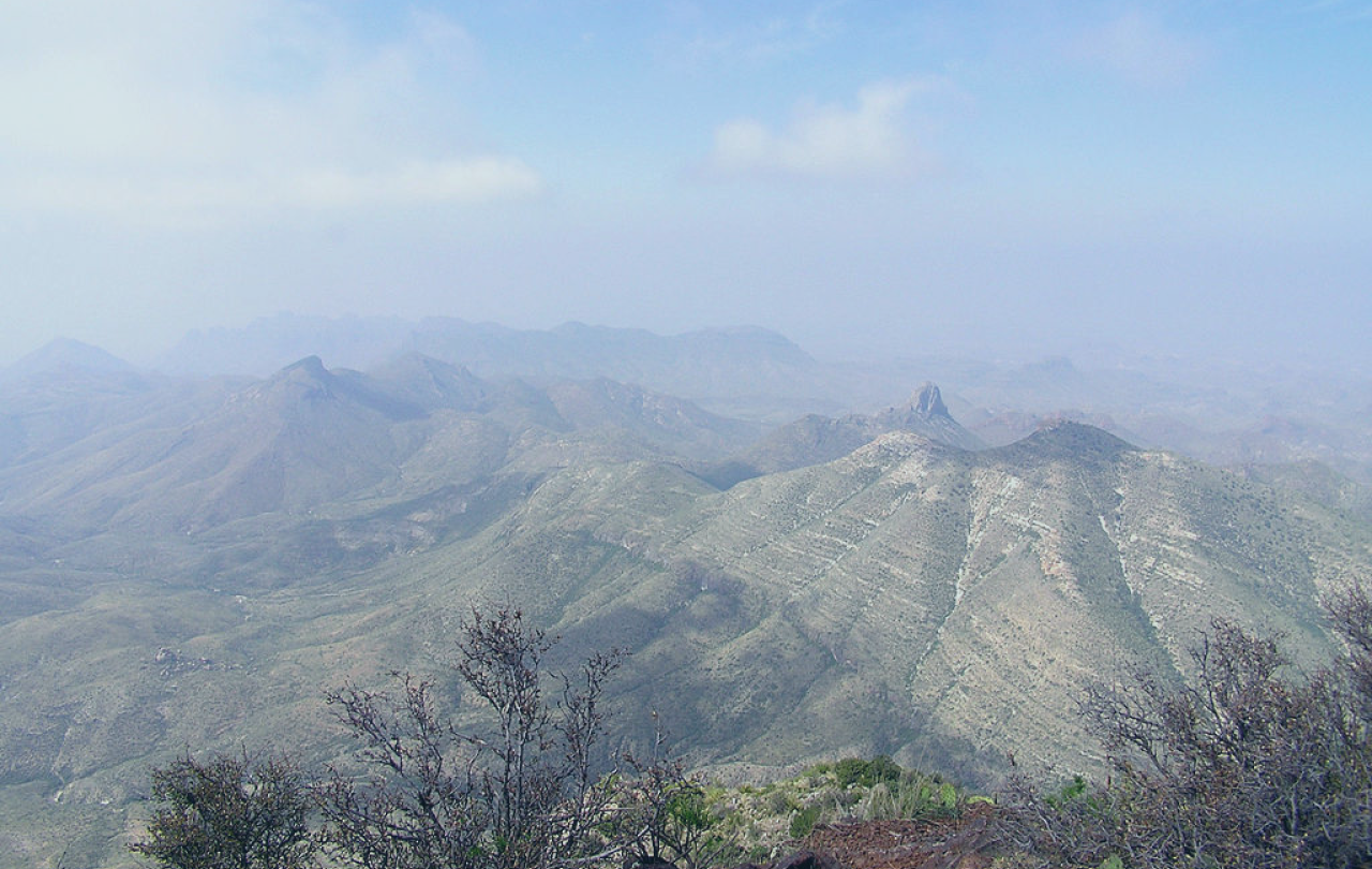 A view of a lightly misted valley to mountains in a desert area.