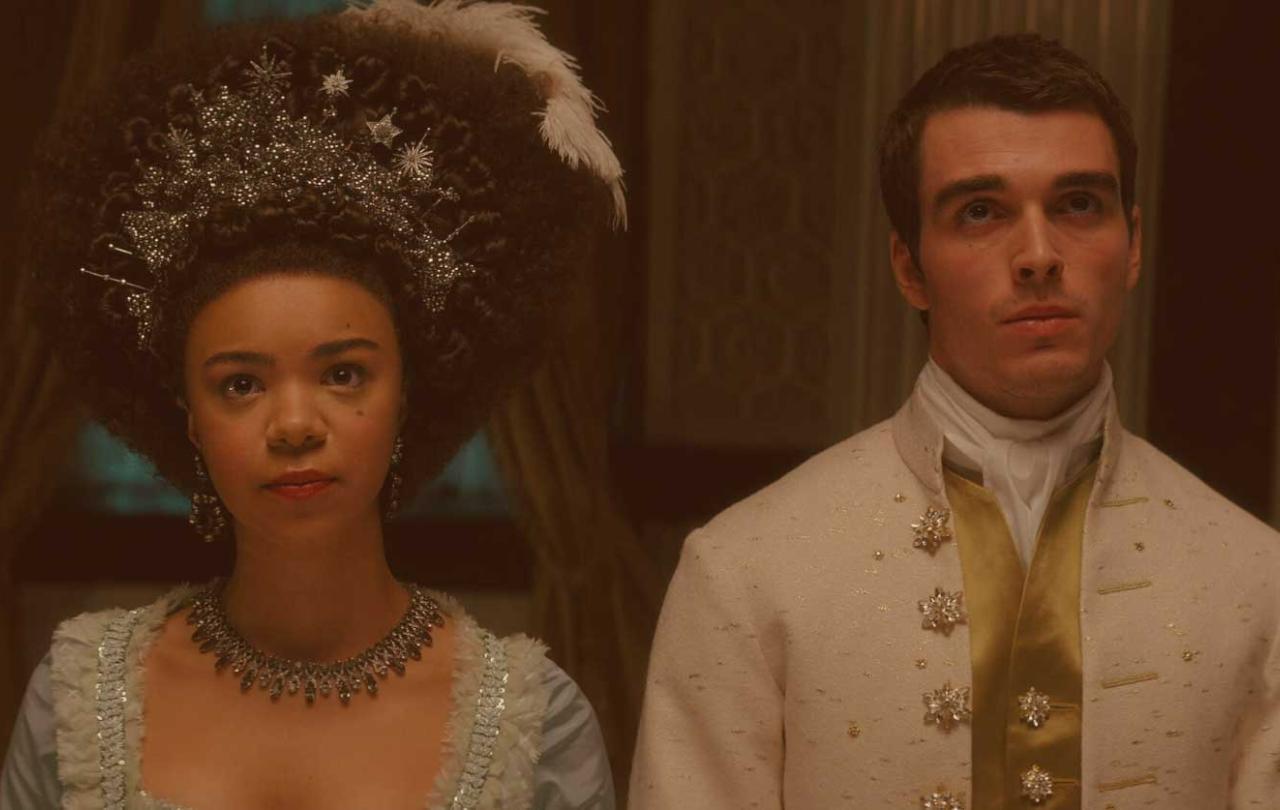 A regency queen and king stand beside each other looking pensive.
