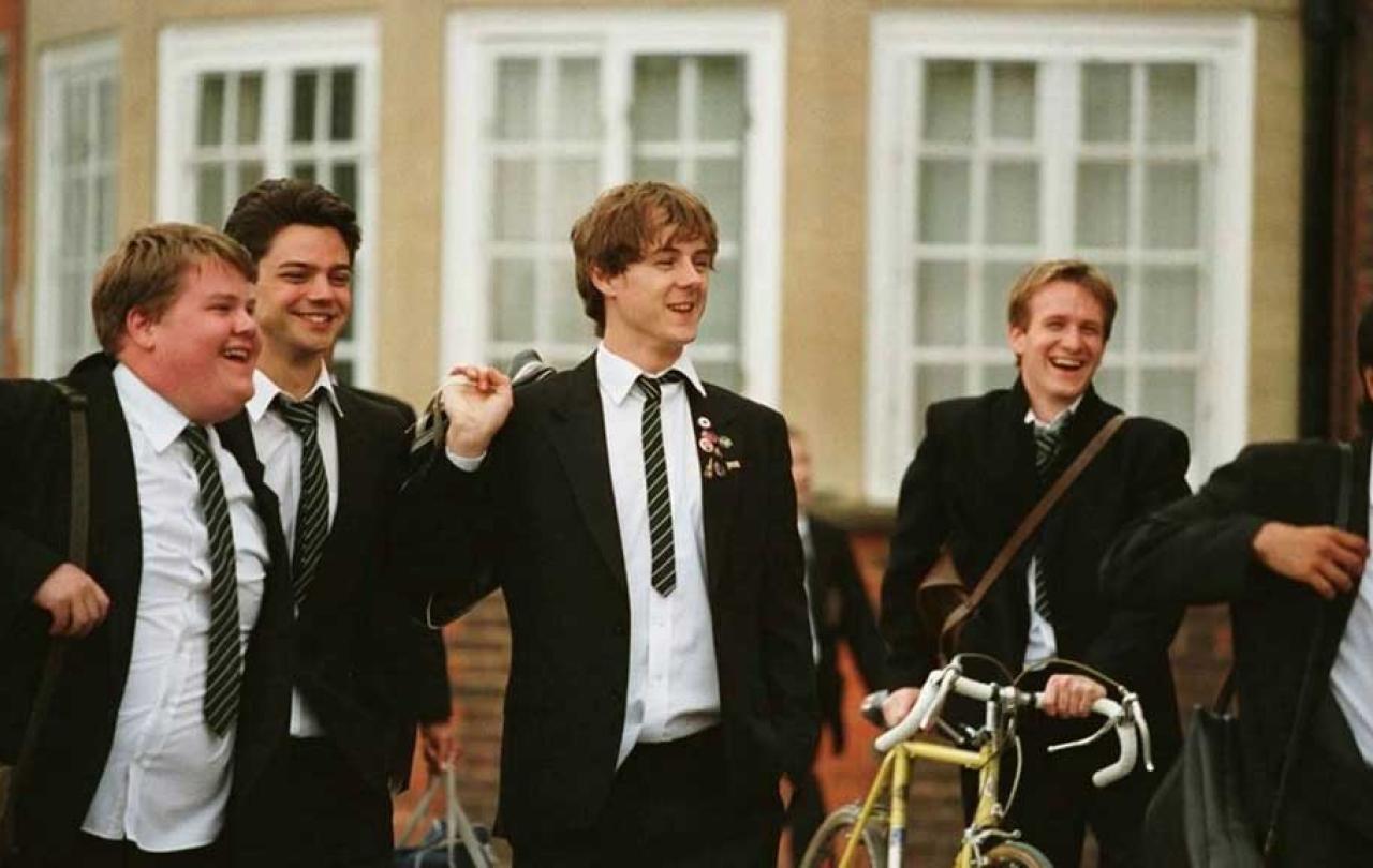 School students walk across a playground confidently talking and laughing with us