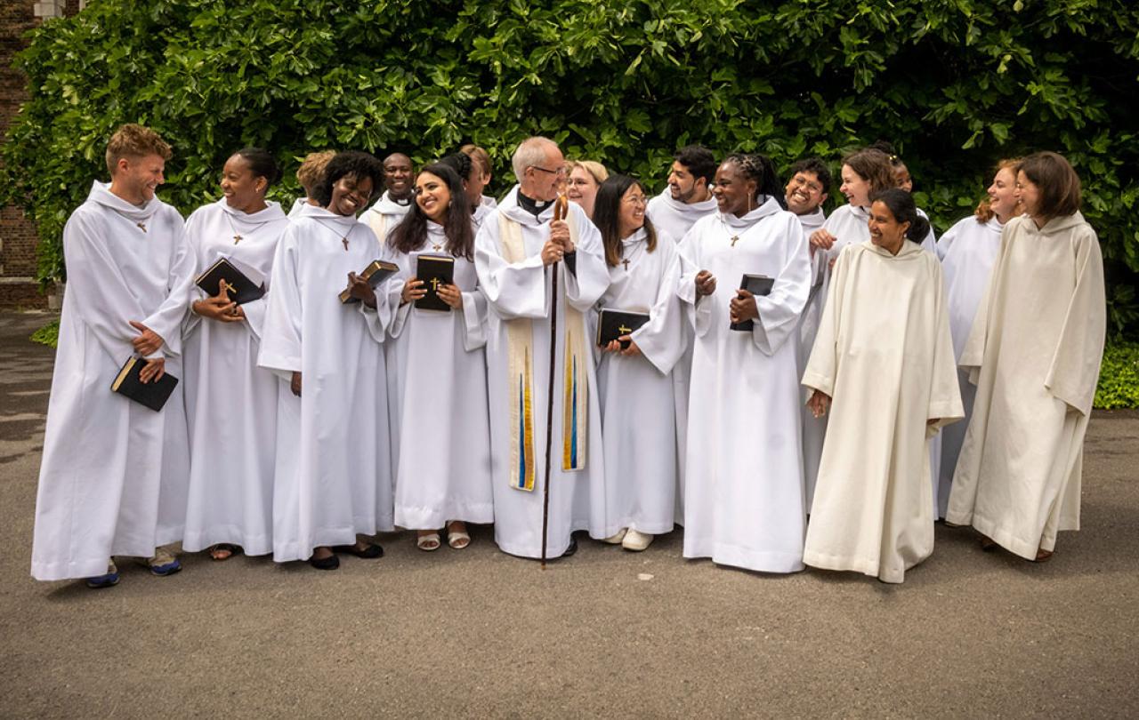 A group of young people wearing white habits stand and laugh with each other.