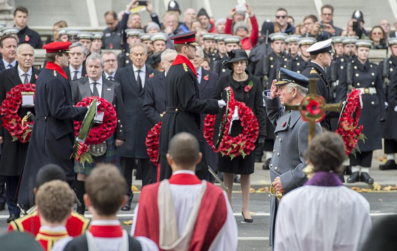 Princes and army officers walk away from a war memorial while others look on.