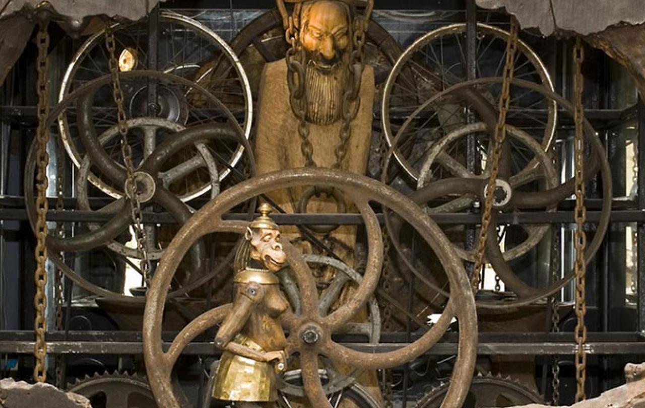 A close-up of a complex clock mechanism featuring small statues within it.