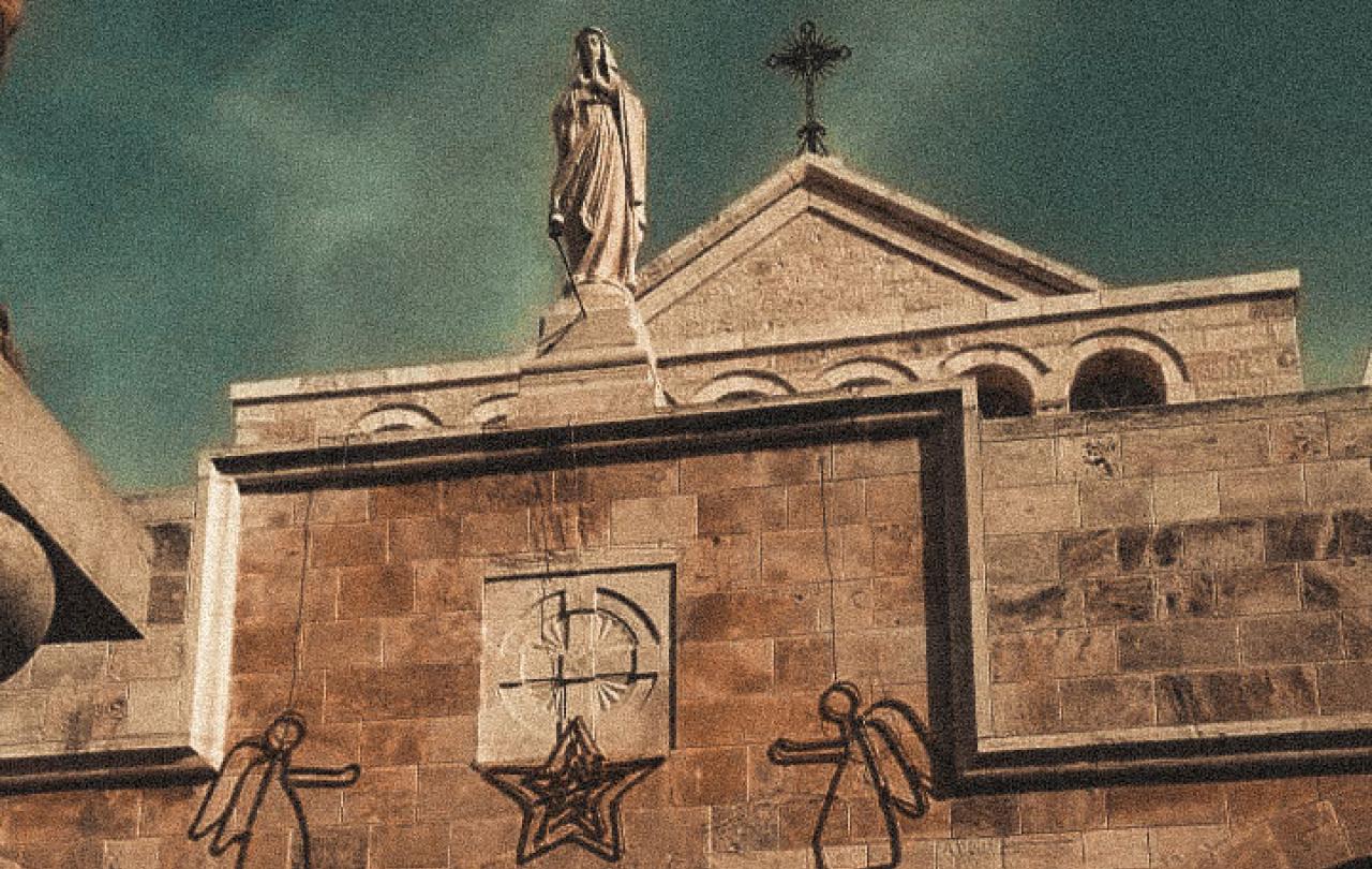 A church gable featuring a cross, a Madonna and angel Christmas decorations.