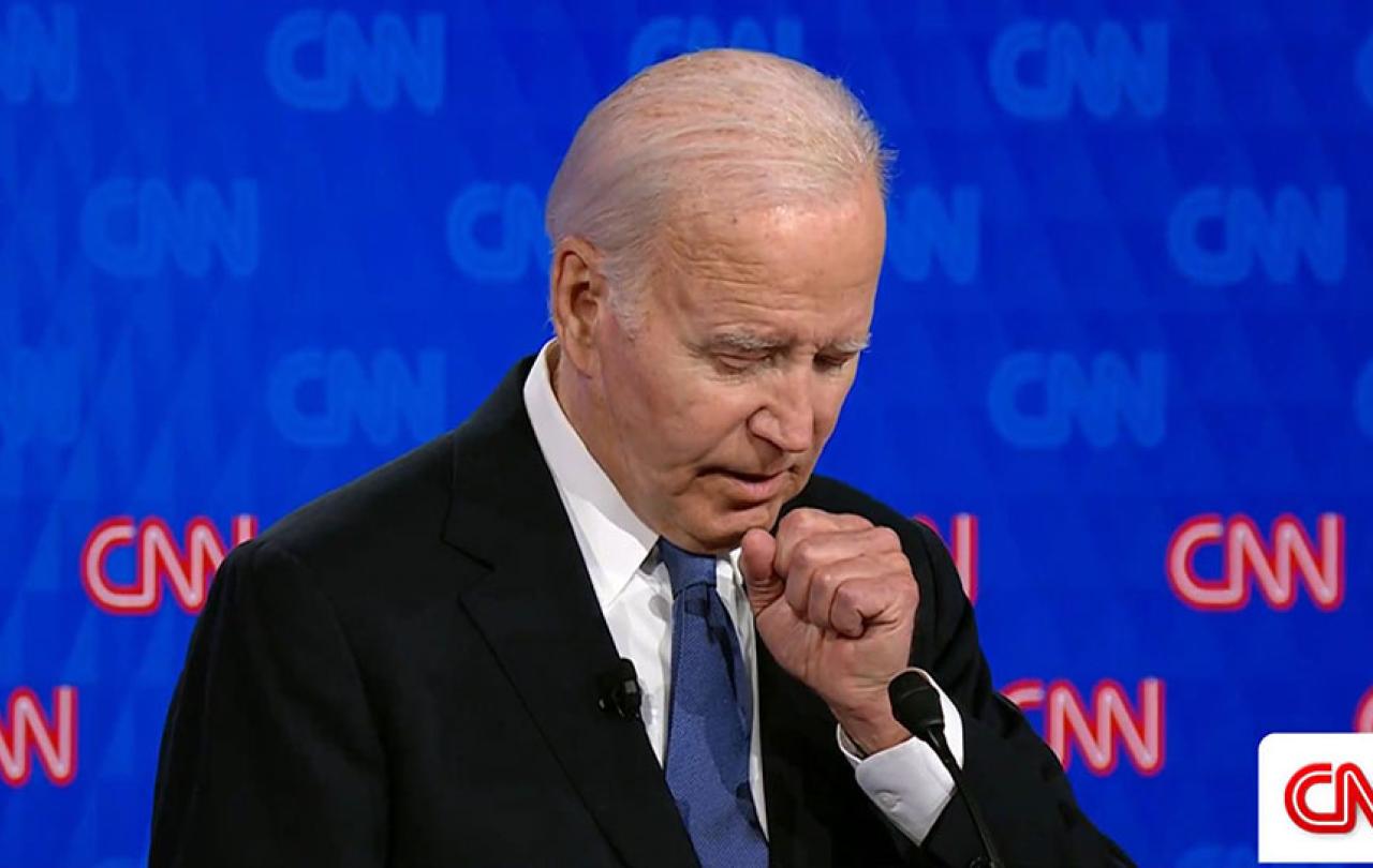 Joe Biden holds a fist to his chest as he stands and speaks.