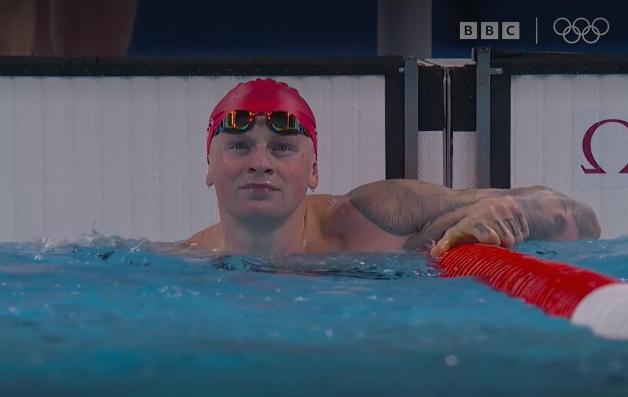 A swimmer at the end of a race, looks to the result screen.