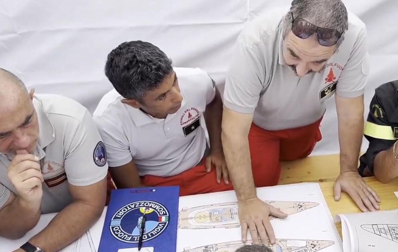 Rescue workers look at the plan of a yacht.