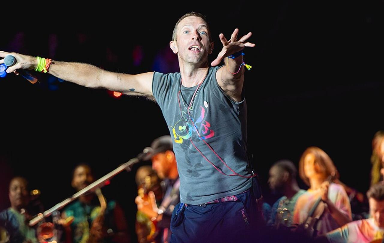 A singer on a stage holds out his arms to conduct the crowd.