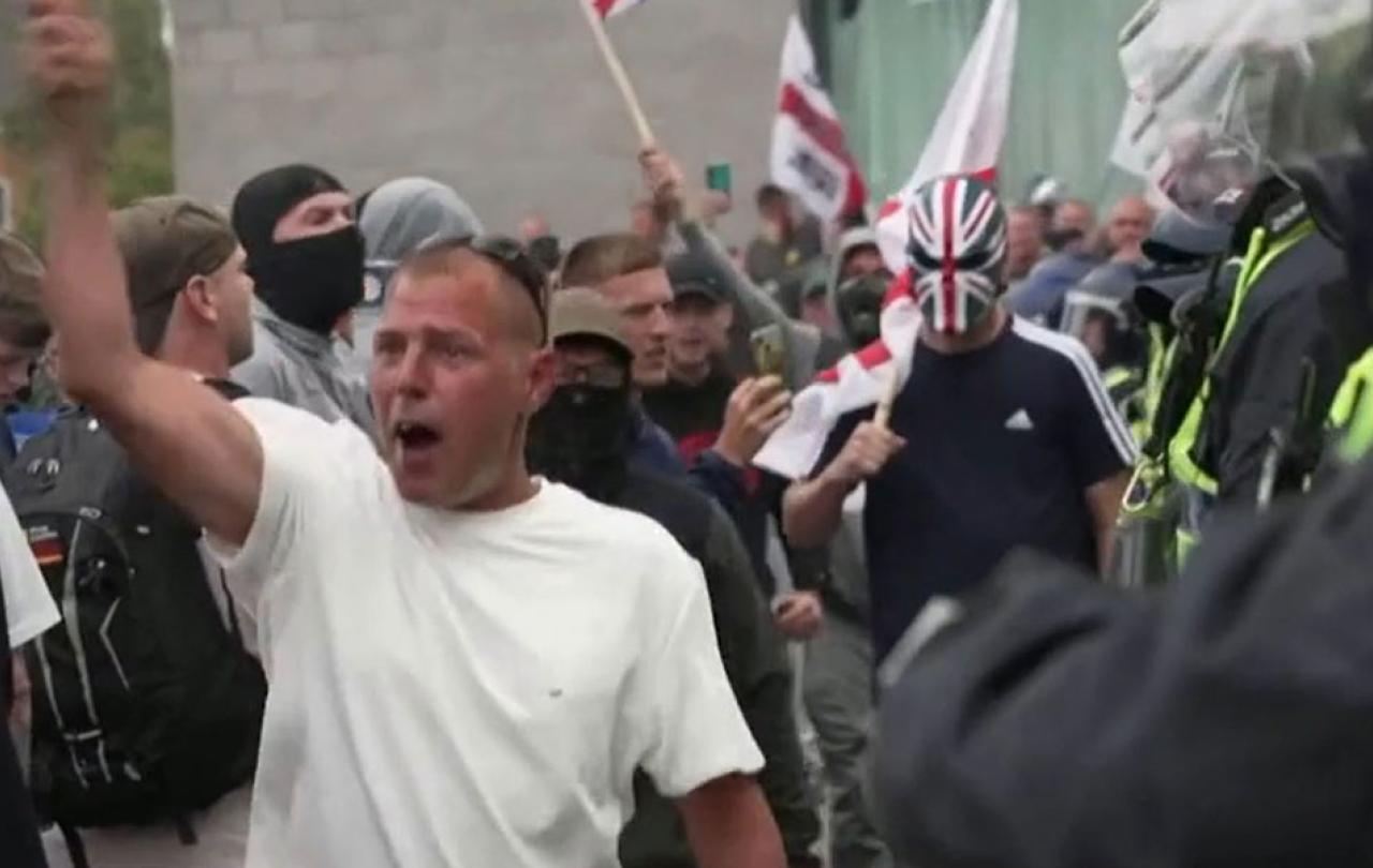 Rioters confront police, one wearing a sinister Union Jack mask