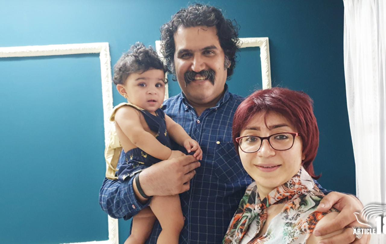 A toddler is held by her father while he stands next to her mother.